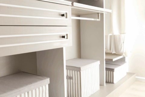 Custom closet built-ins with organized drawers and fabric storage boxes.