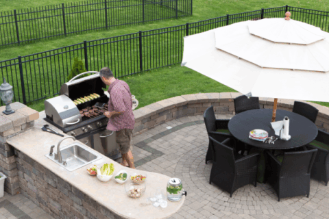 Outdoor stone kitchen island with stainless steel grill and dining area