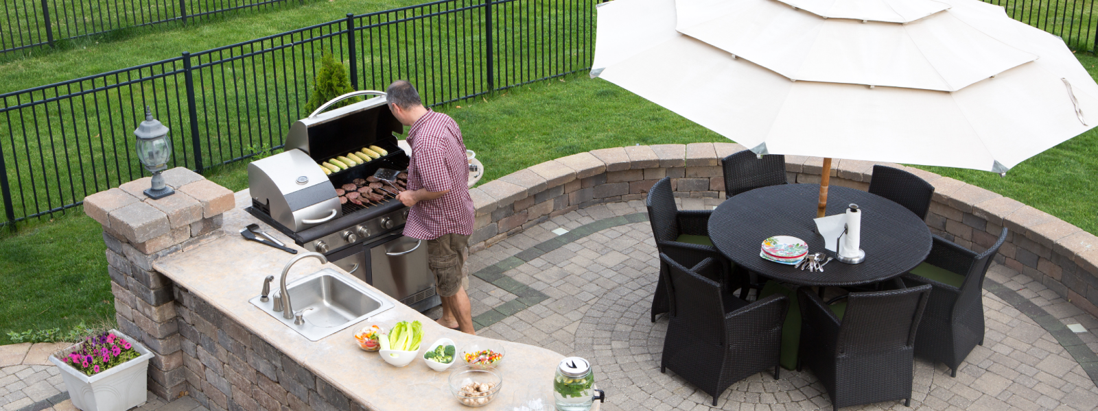 Outdoor stone kitchen island with stainless steel grill and dining area